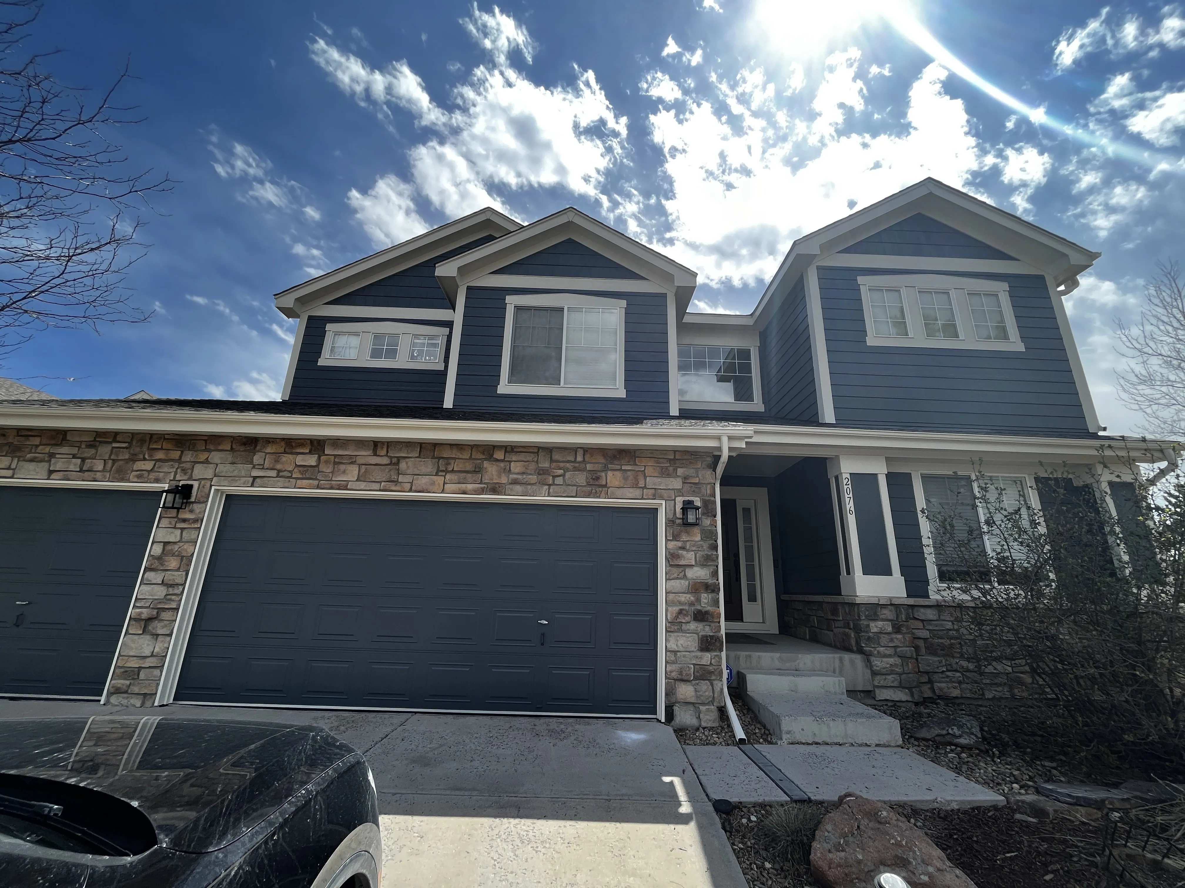 Exterior house painting in Castle Rock — navy home with stone accents and dark garage doors