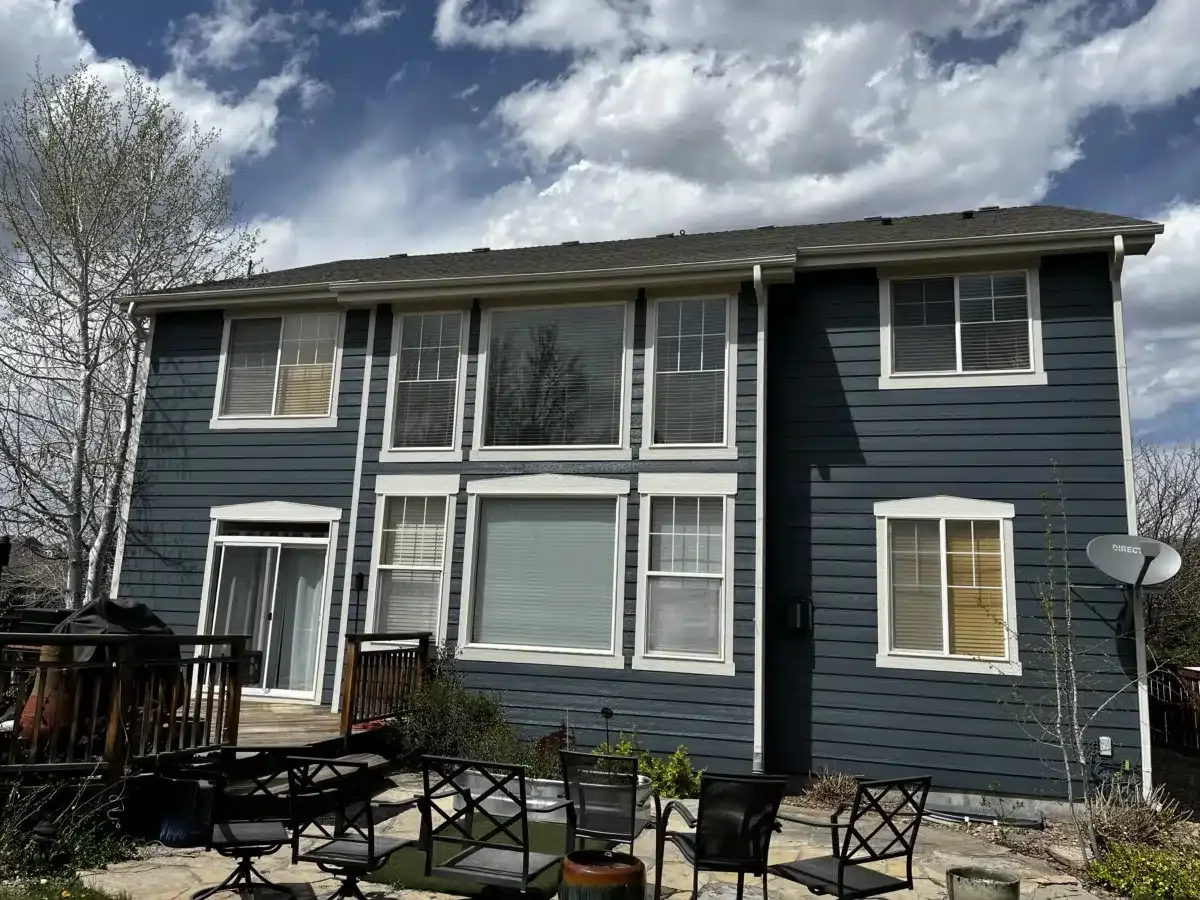 Dark gray two-story home with deck after exterior repaint