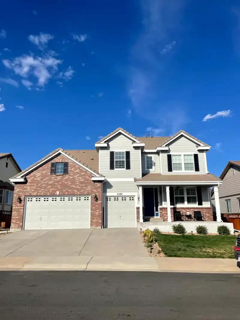 Tan two-story home with three-car garage after exterior repaint